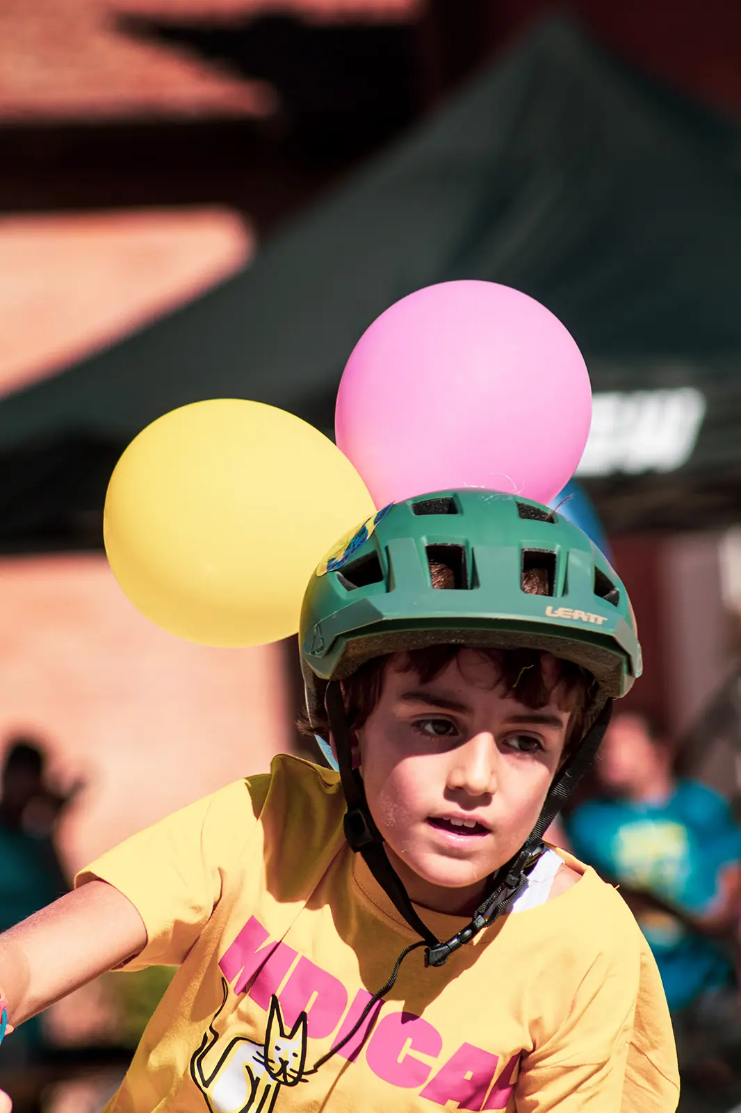 Bambino con palloncini sul casco verde